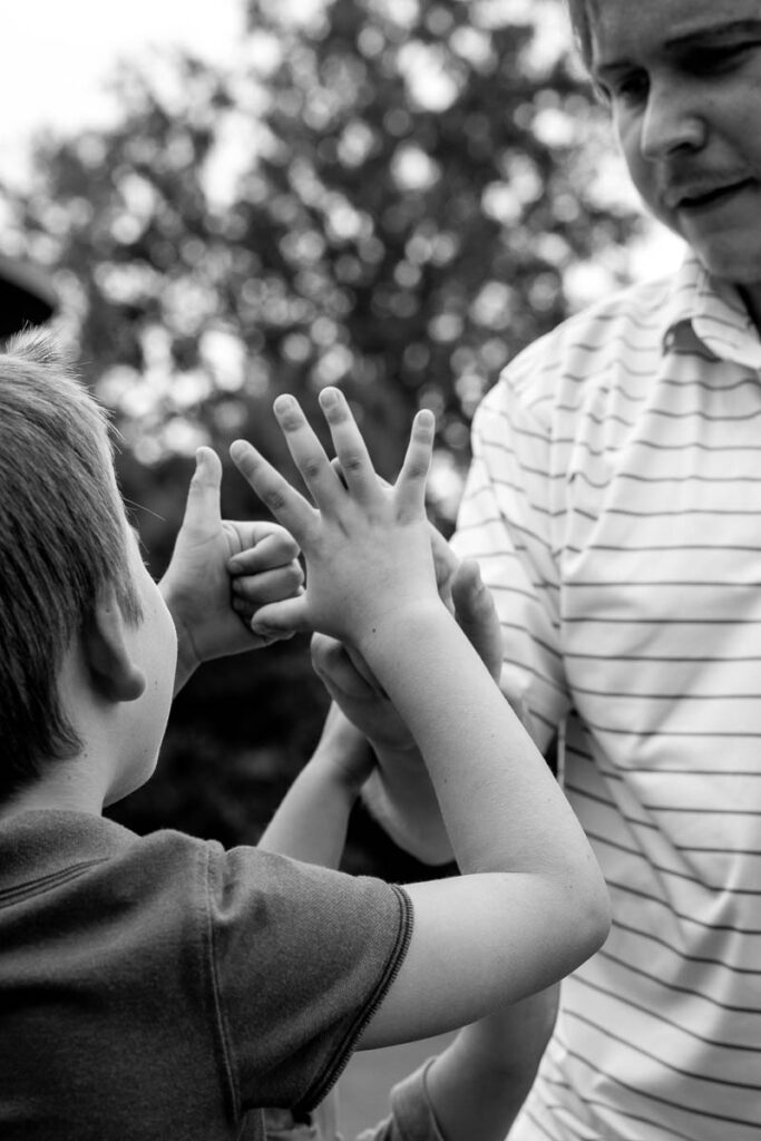 A boy shows his uncle how many years old he is by showing 6 fingers while his uncle counts them.