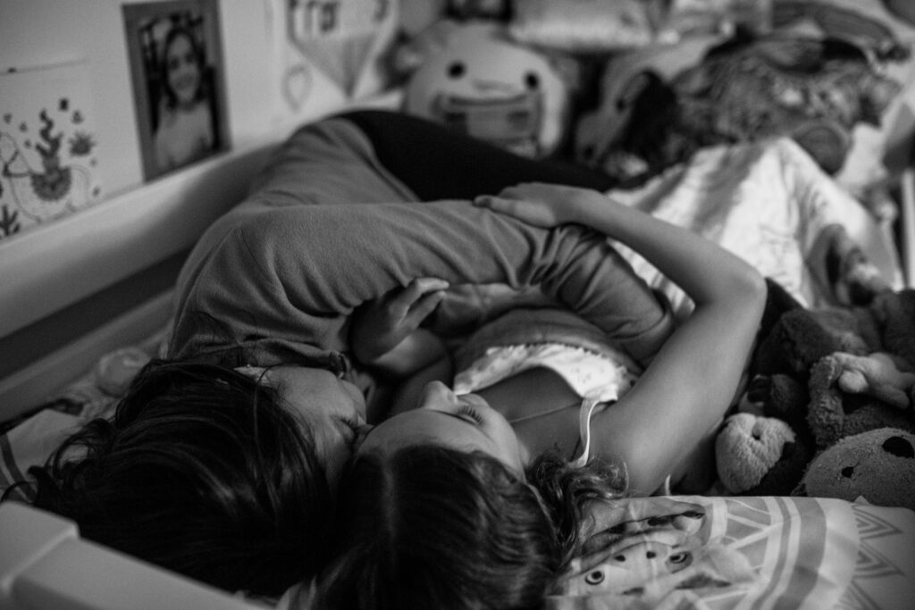 A mom and her daughter share a moment cuddling during bedtime routine. 